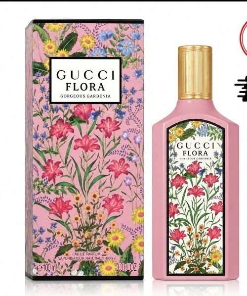 Gucci Flora Eau de Parfum bottle and its matching outer packaging box, both decorated with a vibrant pink floral pattern featuring lilies and wildflowers, with a gold cap on the bottle.