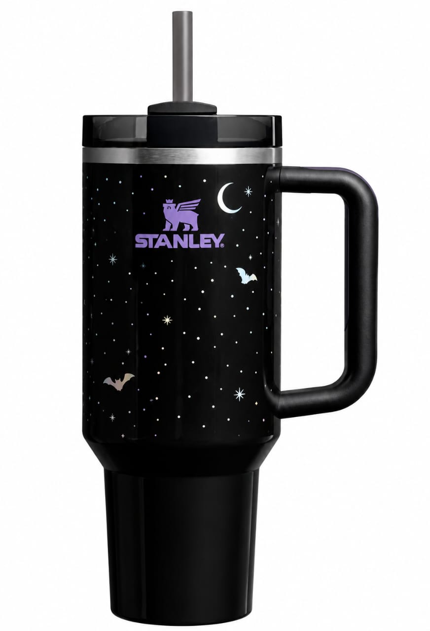 A black Stanley tumbler with a handle and straw, decorated with a purple and white starry night sky pattern, shown on a plain white background.
